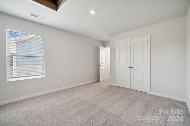 unfurnished bedroom featuring a closet and light colored carpet