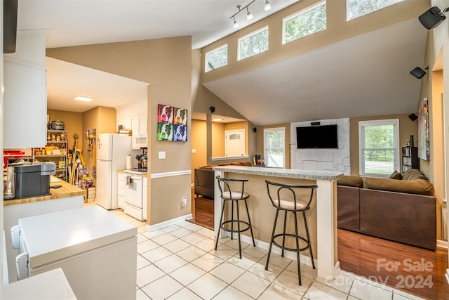 kitchen with white appliances, light tile flooring, white cabinetry, rail lighting, and kitchen peninsula