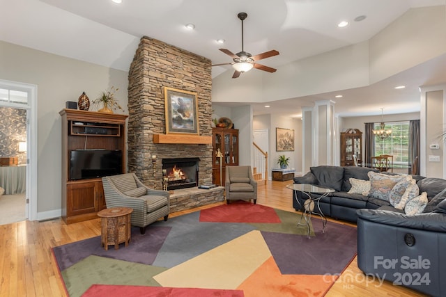 living room featuring ceiling fan, light wood-type flooring, a fireplace, and high vaulted ceiling