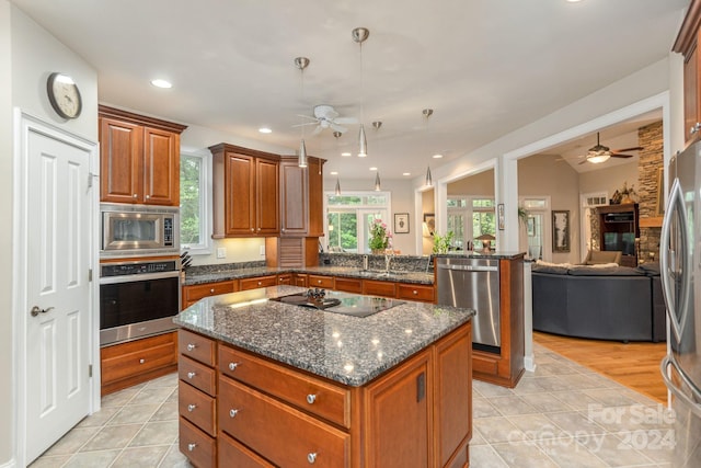 kitchen with pendant lighting, a center island, stainless steel appliances, dark stone counters, and light tile patterned floors