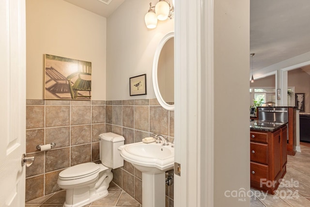 bathroom featuring toilet, tile patterned flooring, and tile walls