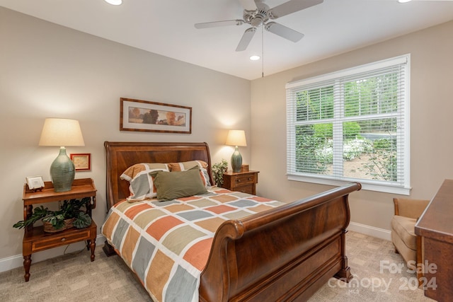 bedroom featuring ceiling fan, light colored carpet, and multiple windows