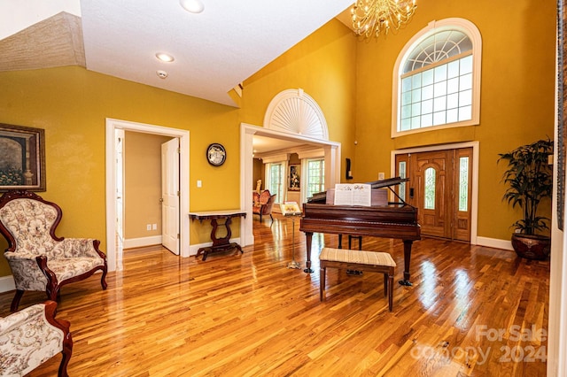 foyer featuring a chandelier, wood-type flooring, and high vaulted ceiling