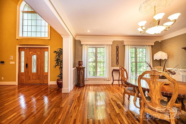 entrance foyer featuring hardwood / wood-style floors, a notable chandelier, ornamental molding, and ornate columns