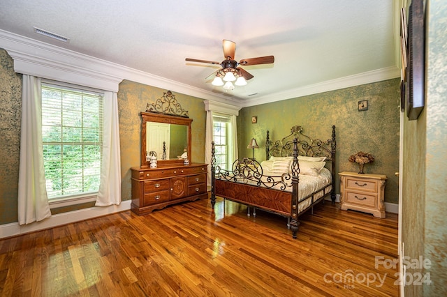 bedroom featuring ornamental molding, wood-type flooring, multiple windows, and ceiling fan