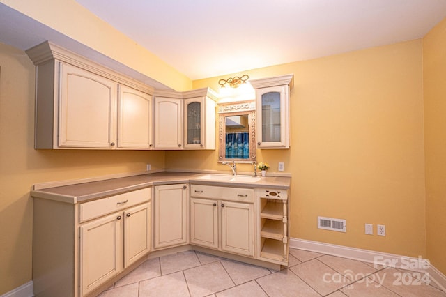 kitchen with sink, cream cabinets, and light tile floors