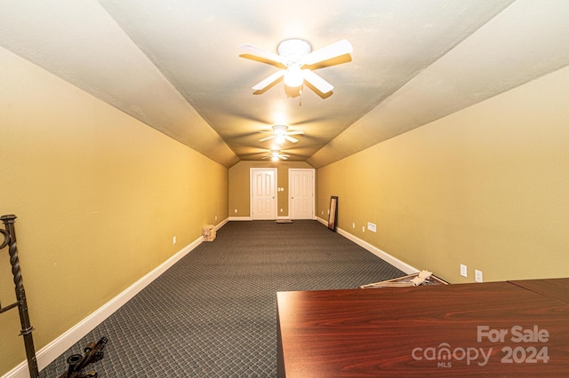 interior space with vaulted ceiling, ceiling fan, and dark carpet