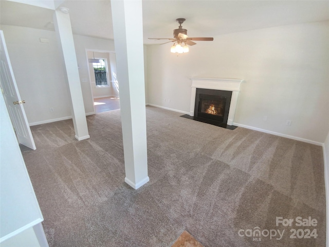 unfurnished living room featuring ceiling fan and dark carpet