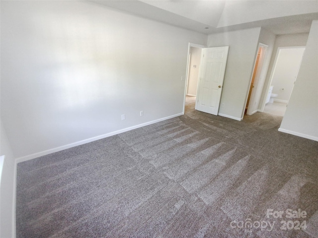 unfurnished bedroom with lofted ceiling and dark carpet