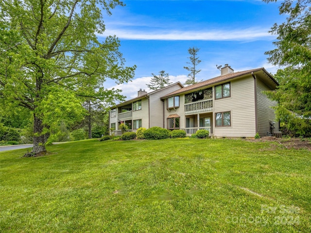 view of front of house featuring a front lawn and a balcony