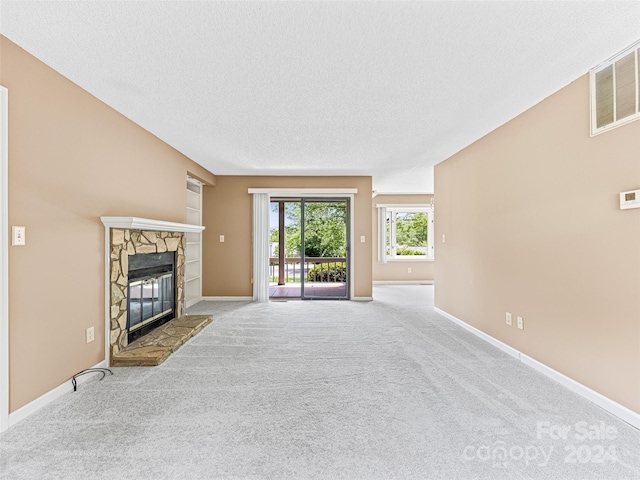 unfurnished living room with a textured ceiling, a fireplace, and carpet floors