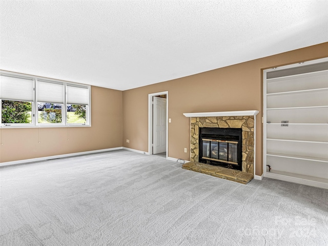 unfurnished living room with carpet flooring, a fireplace, and a textured ceiling