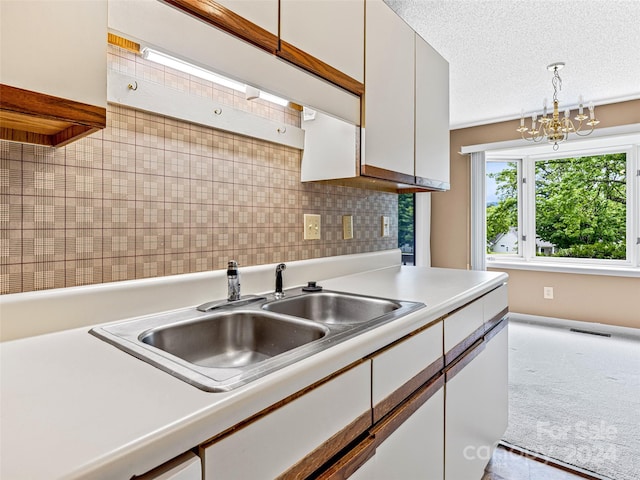 kitchen with a chandelier, hanging light fixtures, tasteful backsplash, sink, and a textured ceiling