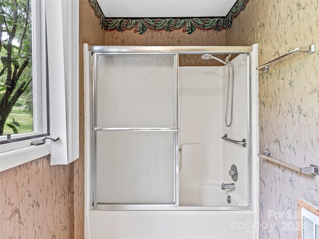 bathroom featuring shower / bath combination with glass door and a textured ceiling