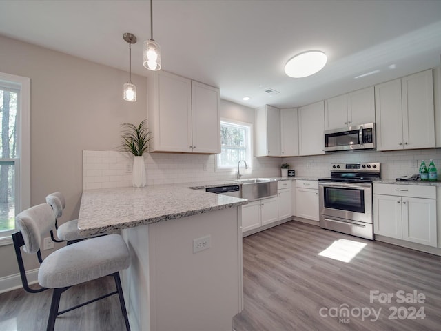 kitchen featuring stainless steel appliances, a kitchen breakfast bar, tasteful backsplash, light stone countertops, and light wood-type flooring