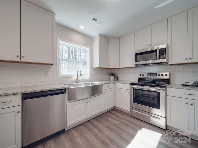 kitchen with white cabinetry, appliances with stainless steel finishes, sink, and light wood-type flooring