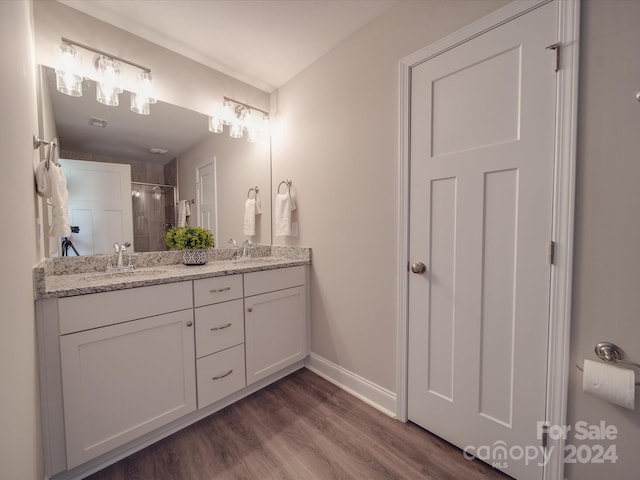 bathroom featuring a shower with shower door, dual vanity, and hardwood / wood-style floors