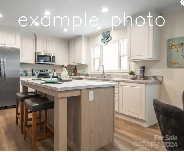 kitchen featuring a kitchen island, light hardwood / wood-style flooring, stainless steel appliances, white cabinets, and sink