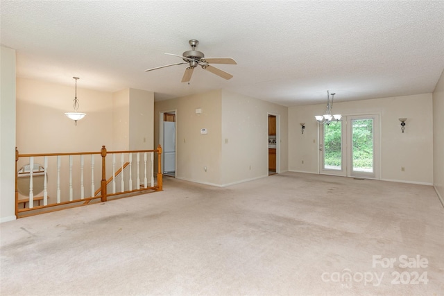 empty room with light carpet, a textured ceiling, and ceiling fan with notable chandelier