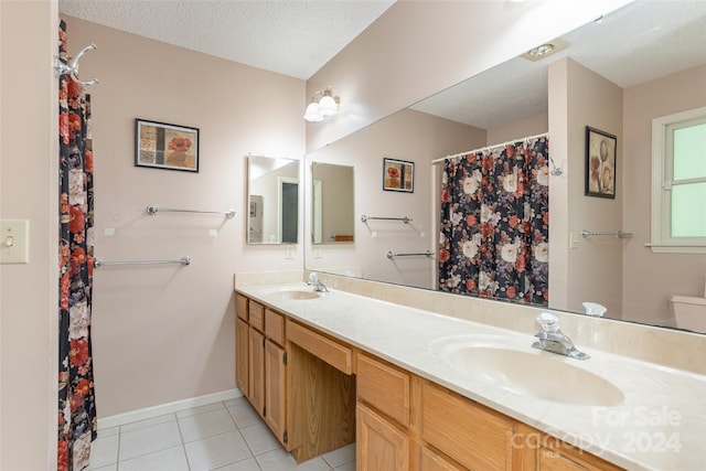 bathroom featuring tile patterned flooring, vanity, and a textured ceiling