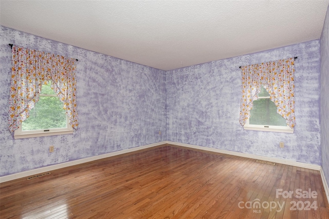 empty room with hardwood / wood-style floors and a textured ceiling