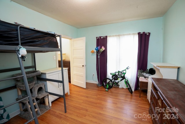 bedroom featuring a textured ceiling and light hardwood / wood-style flooring