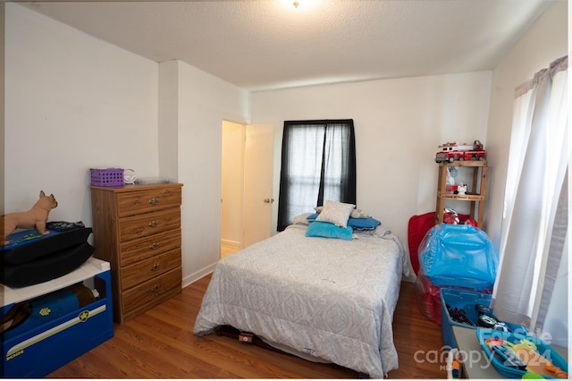 bedroom with hardwood / wood-style floors and a textured ceiling