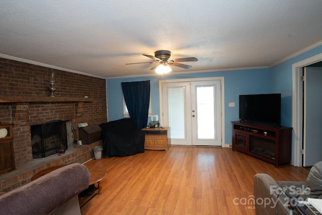 living room featuring light hardwood / wood-style floors, a brick fireplace, french doors, a textured ceiling, and ornamental molding