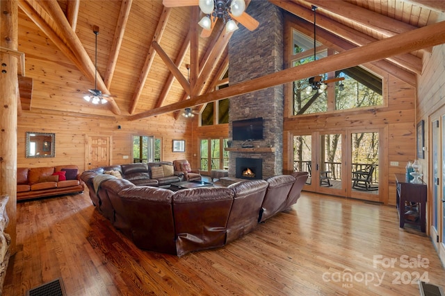 living room featuring wooden walls, ceiling fan, high vaulted ceiling, and light wood-type flooring