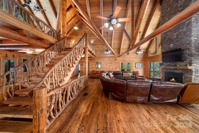 living room with wood ceiling, wood walls, wood-type flooring, and a stone fireplace