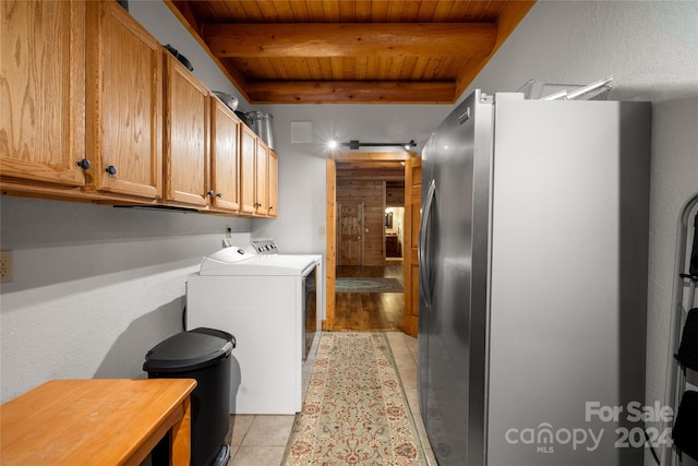 laundry room featuring wooden ceiling, cabinets, light tile floors, and washer and clothes dryer