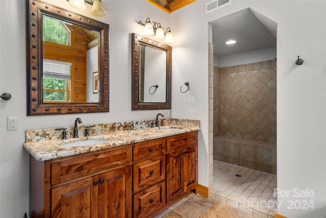 bathroom with plenty of natural light, tile floors, a tile shower, and double sink vanity