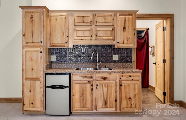 kitchen with tasteful backsplash, dishwasher, light tile floors, and sink