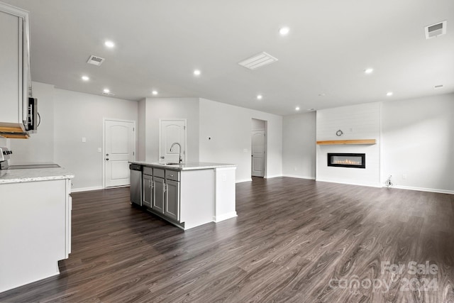 kitchen featuring a kitchen island with sink, a large fireplace, dark hardwood / wood-style flooring, appliances with stainless steel finishes, and sink