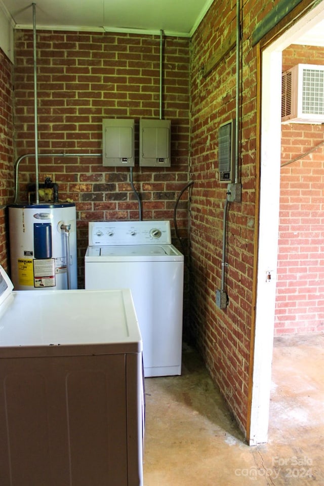 washroom featuring separate washer and dryer, electric water heater, and brick wall