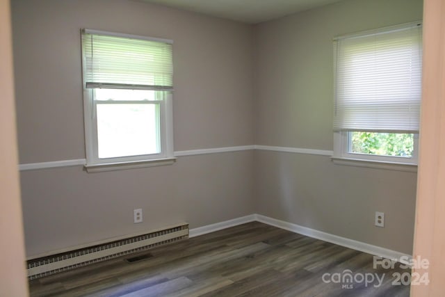 spare room featuring plenty of natural light, baseboard heating, and dark wood-type flooring