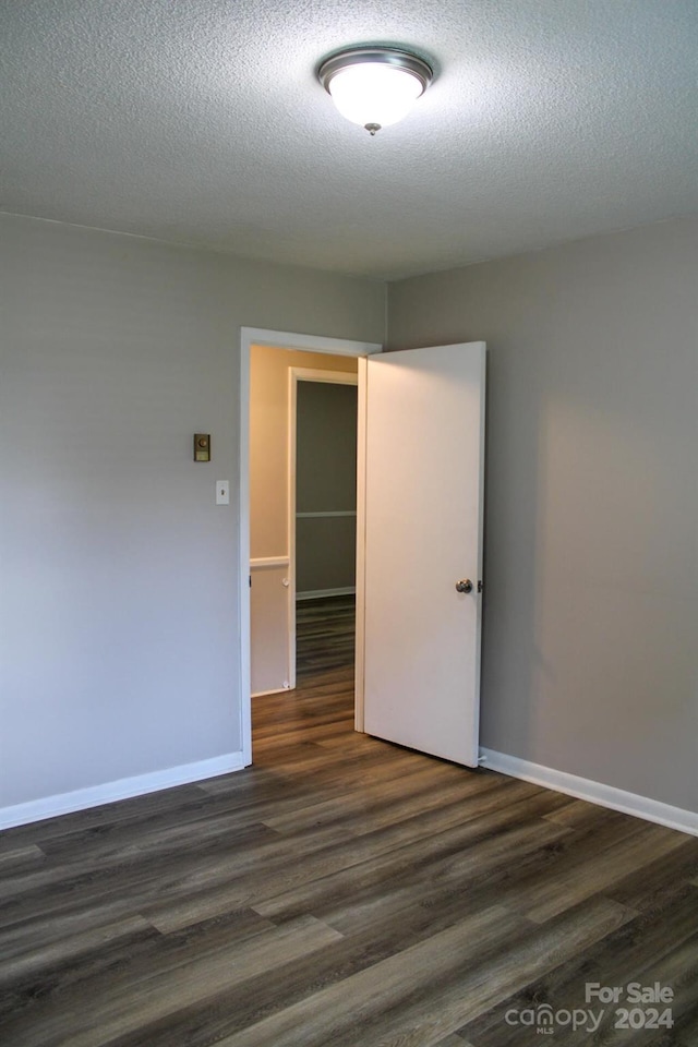 empty room with dark hardwood / wood-style floors and a textured ceiling