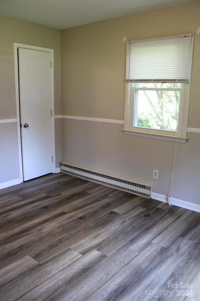 empty room featuring hardwood / wood-style floors and a baseboard heating unit