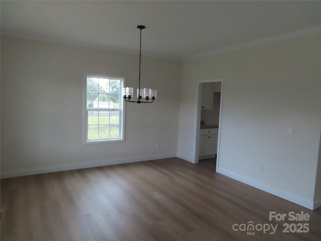 empty room featuring crown molding, hardwood / wood-style floors, and a chandelier