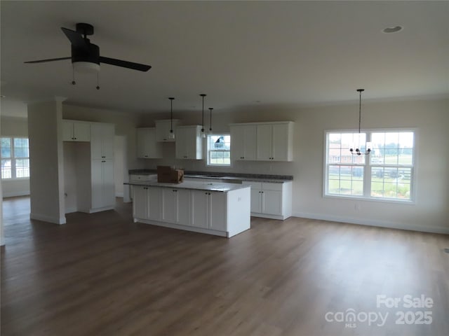 kitchen featuring pendant lighting, hardwood / wood-style floors, white cabinets, a kitchen island, and ceiling fan with notable chandelier