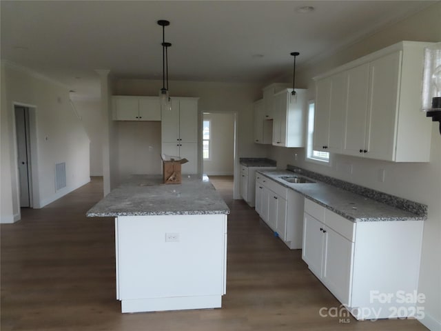 kitchen with a kitchen island, decorative light fixtures, white cabinetry, dark hardwood / wood-style flooring, and light stone countertops