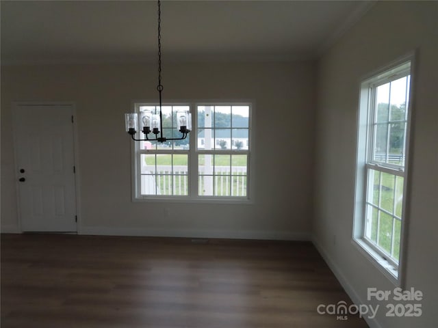 unfurnished dining area featuring ornamental molding, dark hardwood / wood-style floors, and a chandelier