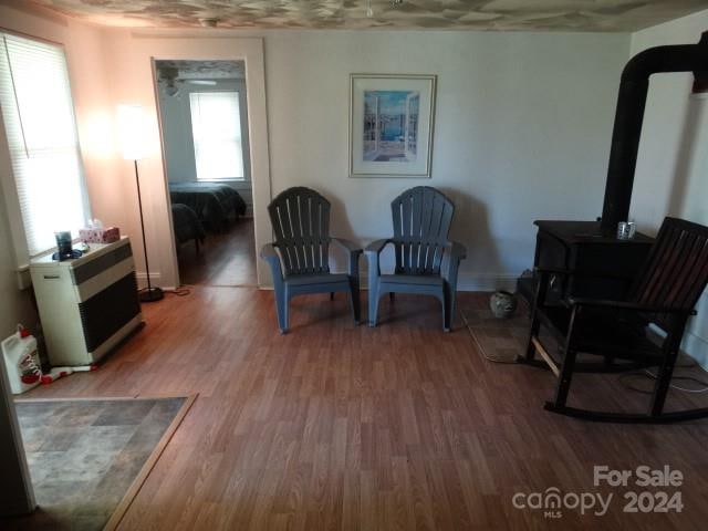 living area with wood-type flooring and a wood stove