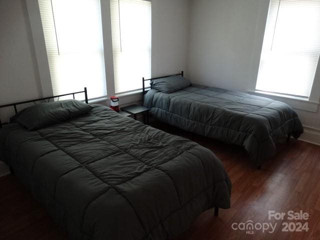 bedroom with multiple windows and dark hardwood / wood-style floors