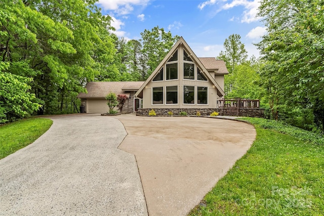 view of front facade featuring a garage, a wooden deck, and a front yard