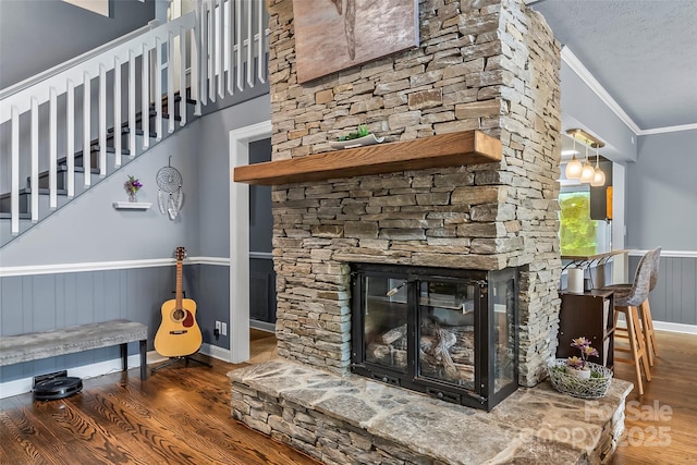 details featuring a textured ceiling, wood-type flooring, ornamental molding, and a fireplace