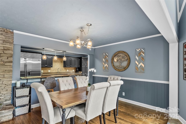 dining area featuring crown molding, sink, dark hardwood / wood-style floors, and a notable chandelier