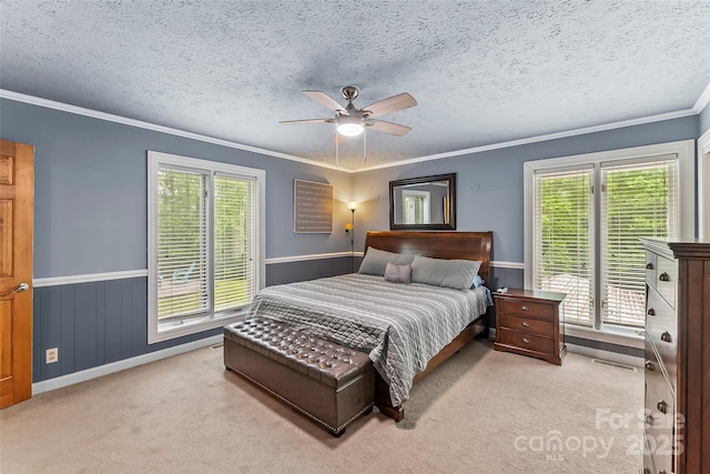 bedroom with a textured ceiling, ceiling fan, light colored carpet, and multiple windows