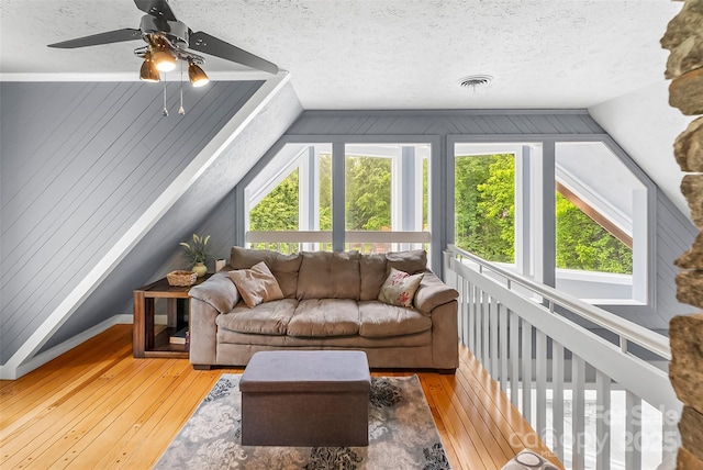 living room with a textured ceiling, plenty of natural light, vaulted ceiling, and wood-type flooring