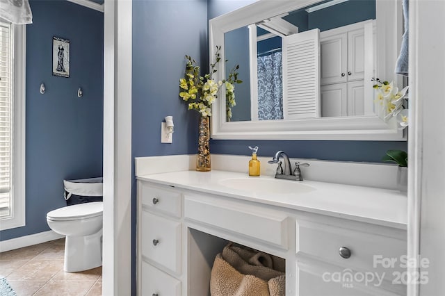 bathroom featuring toilet, a wealth of natural light, tile patterned floors, and vanity